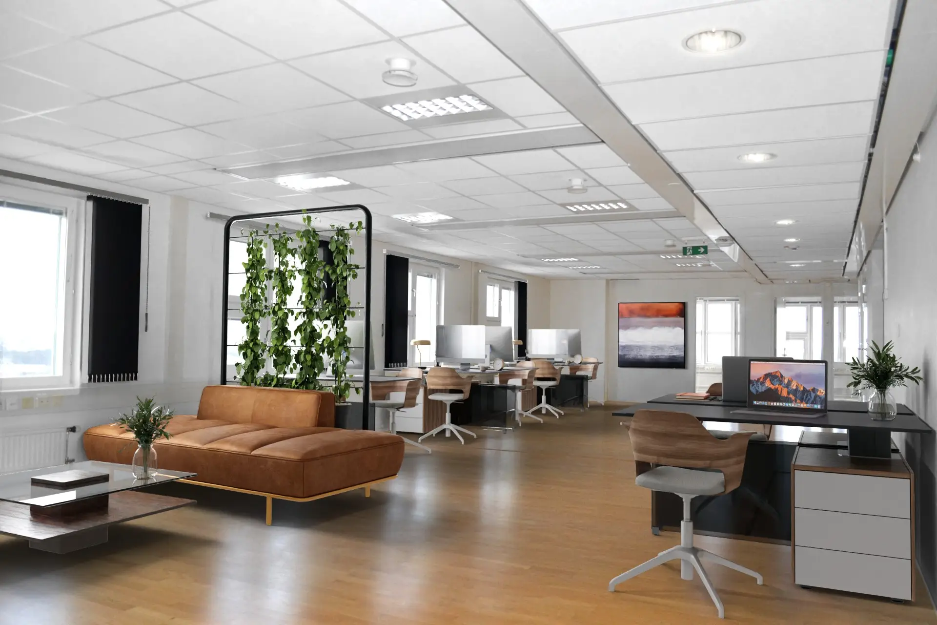 Kontorsyta med flera skrivbord och datorer, en skinnsoffa, stora fönster, gröna växter och en abstrakt målning på väggen. rymlig och starkt upplyst miljö.